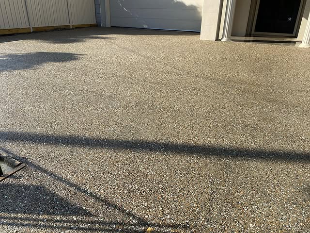 Close-up of a new exposed aggregate driveway in front of a garage