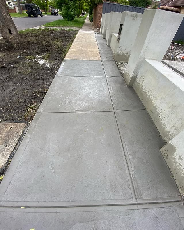 New concrete footpath between a front garden and a rendered fence