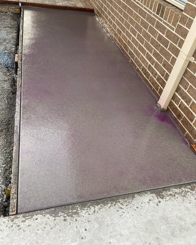 Freshly finished concrete path beside a brick wall