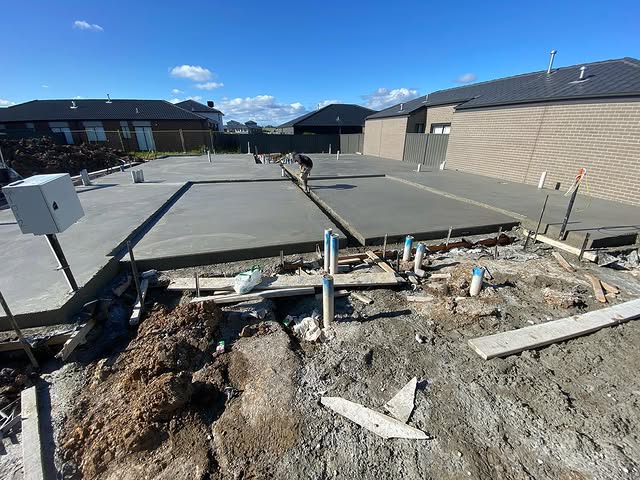 Close view of a finished house slab with plumbing pipes and a meter box