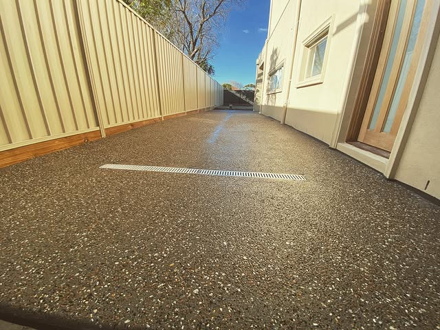 Exposed aggregate side path with a strip drain beside a house