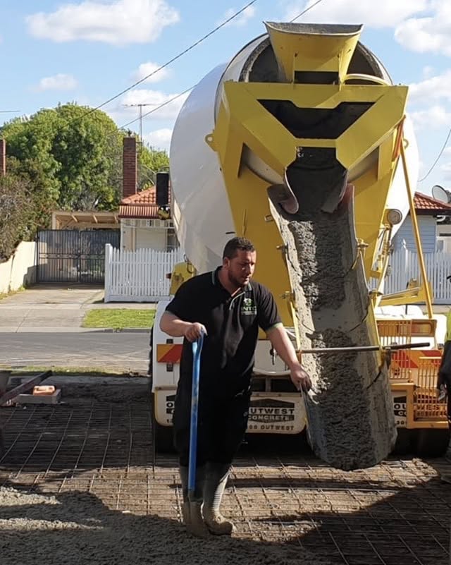Worker guiding concrete from an agitator chute onto steel mesh