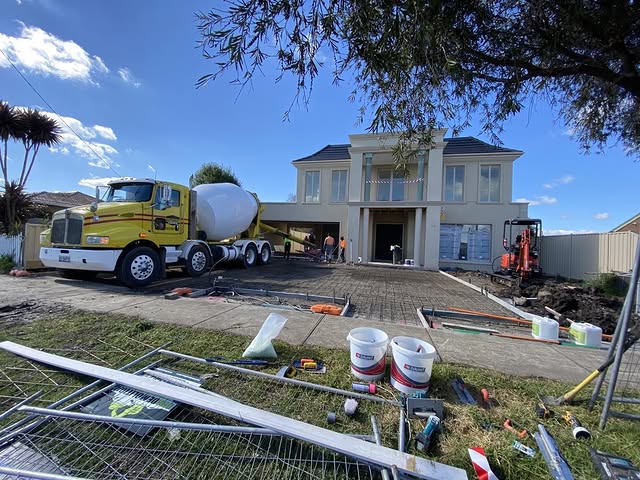 Concrete agitator truck on a driveway in front of a large two-storey home
