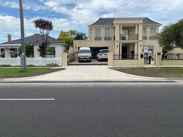 New concrete driveway and crossover in front of a rendered two-storey home