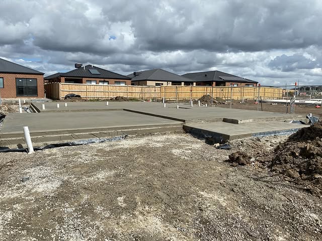 Freshly poured house slabs on a new estate with soil and pipes in front