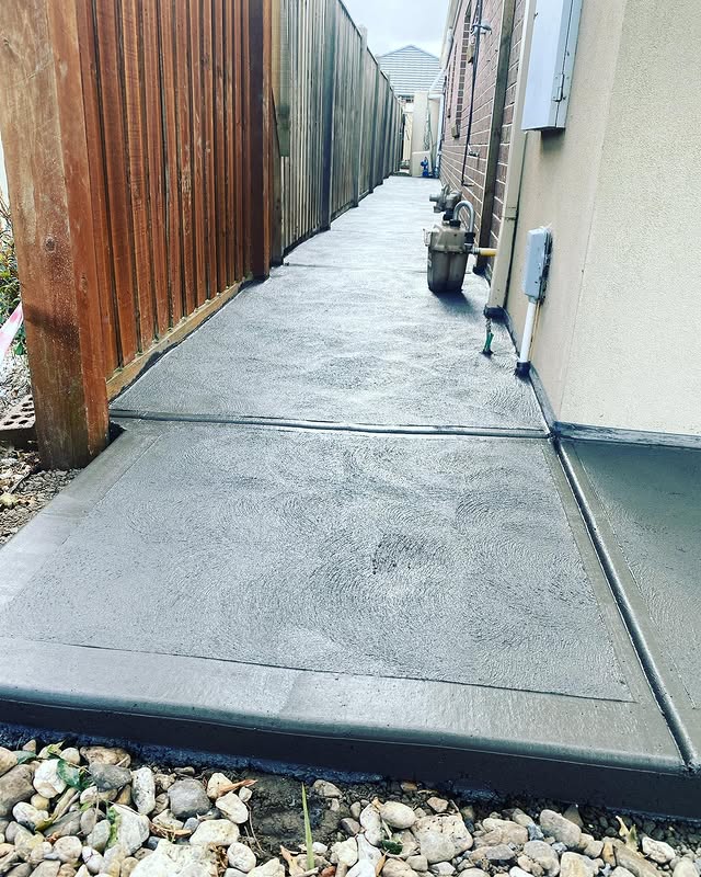 New concrete side path between a timber fence and a house