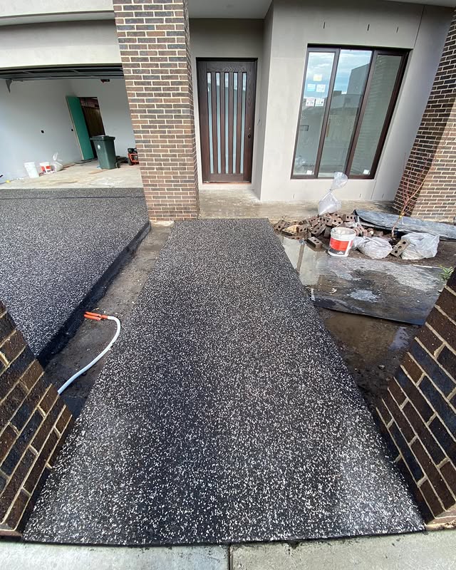 Exposed aggregate path leading to a new home's front door between brick walls