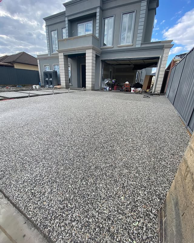 Exposed aggregate driveway in front of a new grey two-storey home