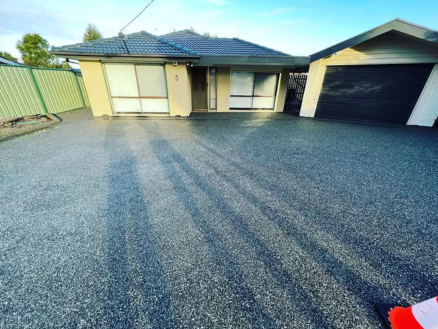 Wide exposed aggregate driveway in front of a brick home and garage