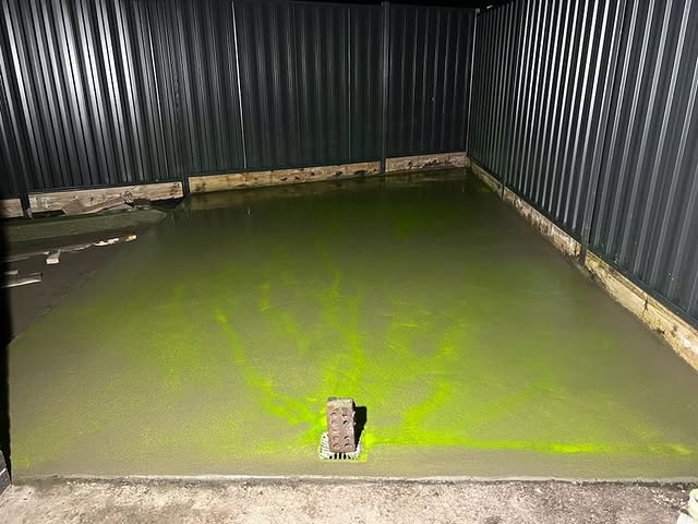 Freshly poured shed slab with a green glow, photographed at night