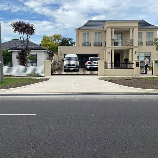 New concrete driveway and crossover in front of a rendered two-storey home