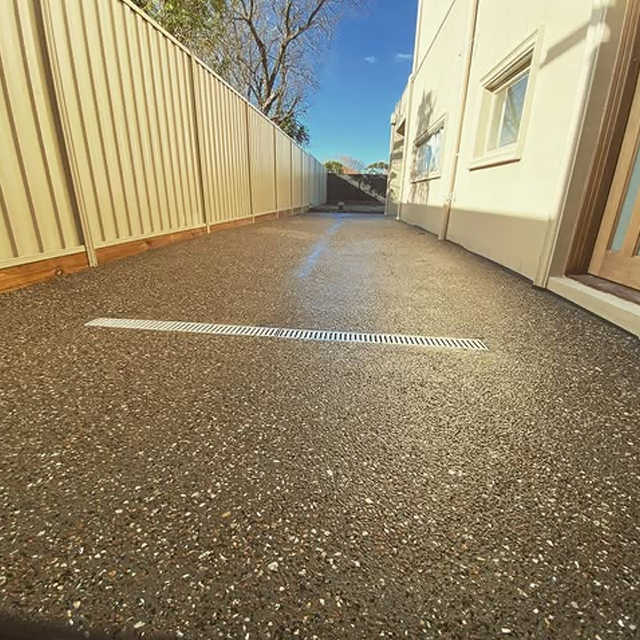Exposed aggregate side path with a strip drain between a fence and a house