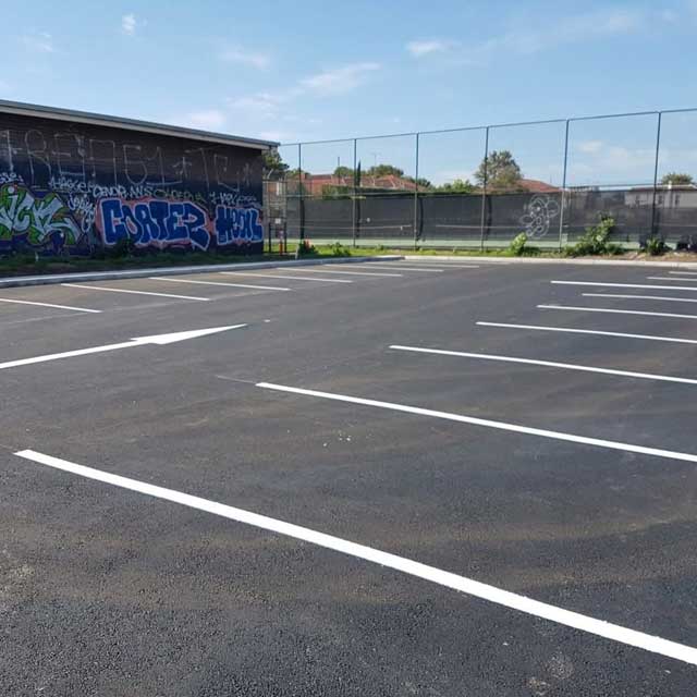 Newly sealed car park with fresh white bay lines and a direction arrow