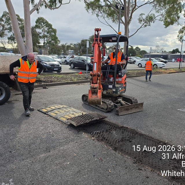 Mini excavator removing a speed hump and digging out asphalt in a car park