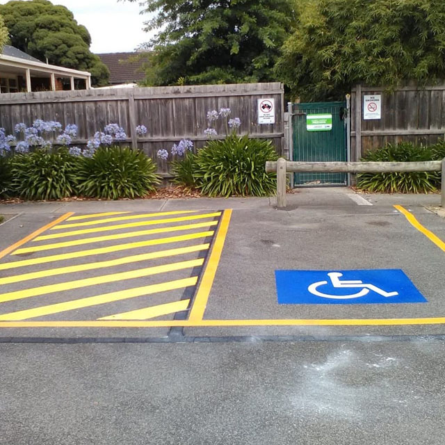 Accessible parking bay with yellow hatched line marking and a wheelchair symbol