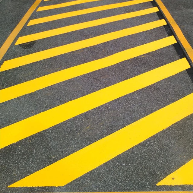 Freshly painted yellow hatched line marking on asphalt