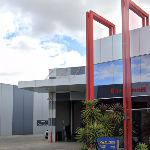 Office entrance with a tall red steel frame and a garden bed out front