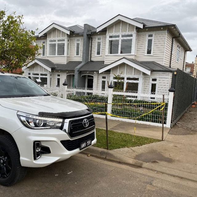 White ute parked outside a new two-storey weatherboard home