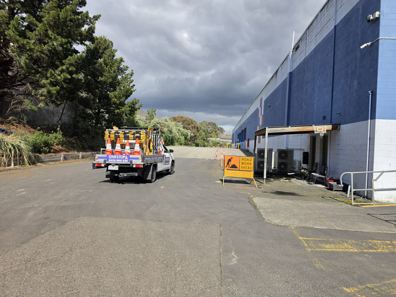 Ute loaded with traffic cones and a roadwork sign beside a warehouse