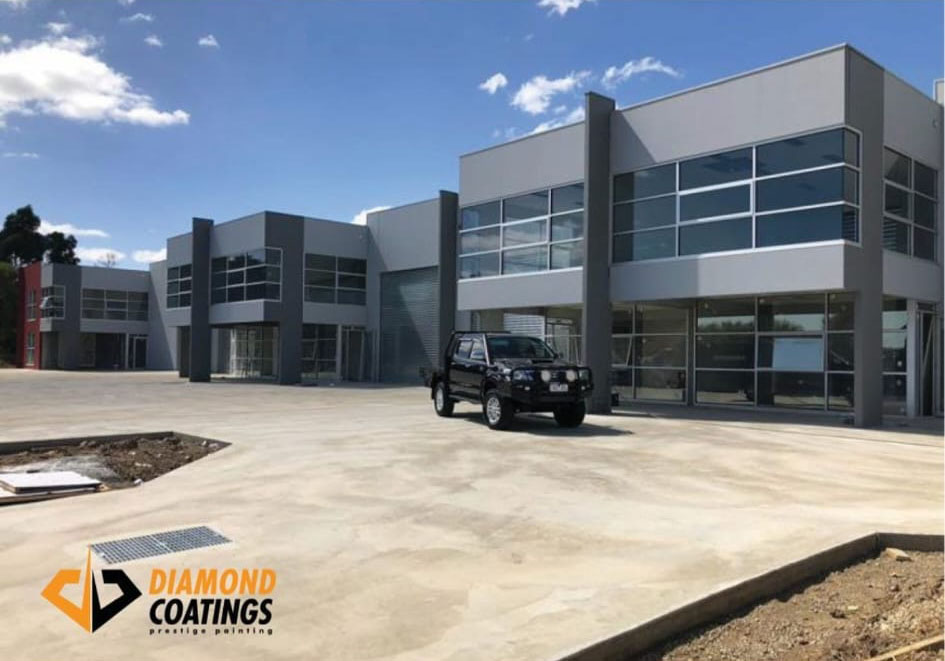 New two-storey commercial units with a concrete forecourt and a black ute