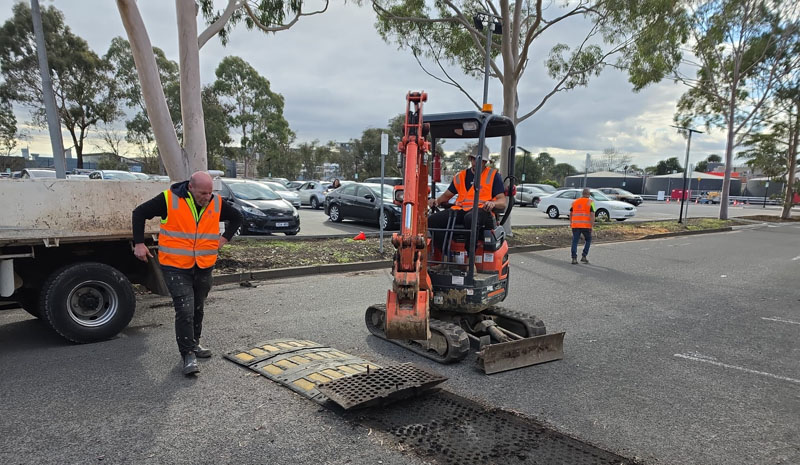 Mini excavator and crew removing a speed hump in a car park
