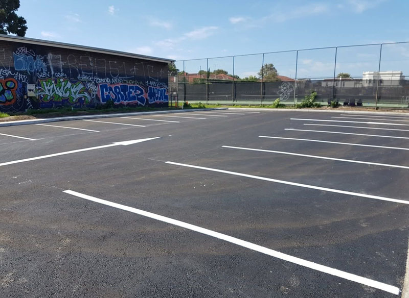 Newly sealed car park with fresh white bay lines and a direction arrow