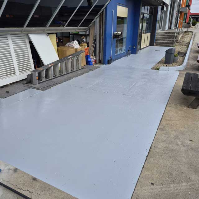 Freshly coated grey walkway in front of a row of commercial shopfronts