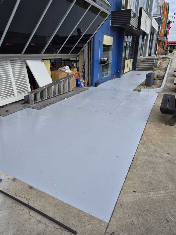 Grey coated concrete walkway outside commercial shopfronts