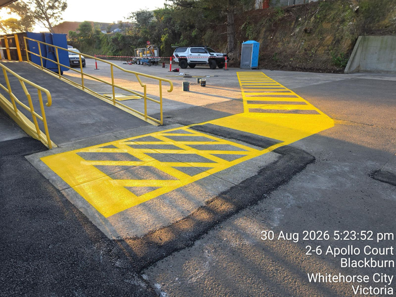New asphalt and yellow hatched line marking at the foot of an access ramp