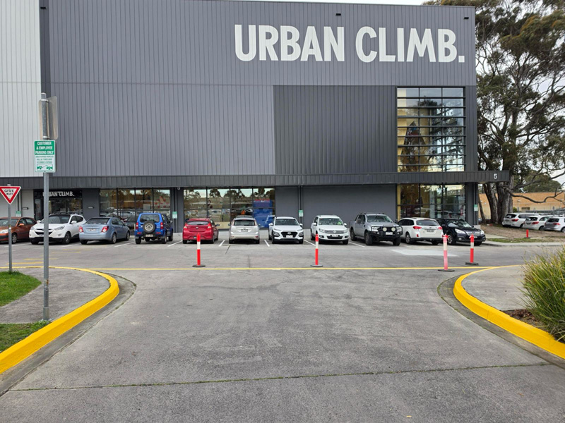 Concrete car park entry with yellow painted kerbs outside a large commercial building
